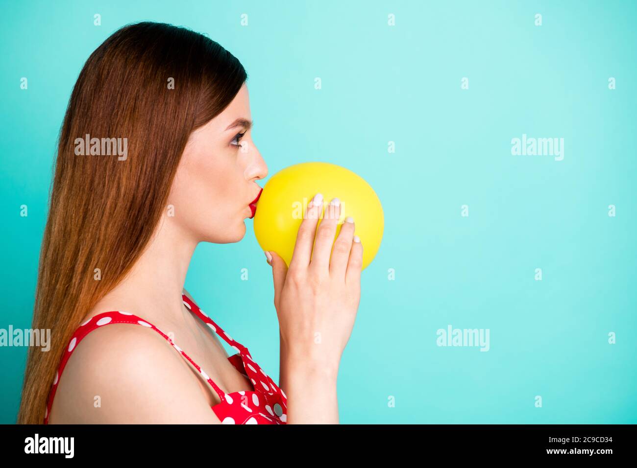 Profile photo of attractive lady look side empty space hold helium air  balloon inside mouth breathe in talk funny voice wear red dotted retro  dress Stock Photo - Alamy
