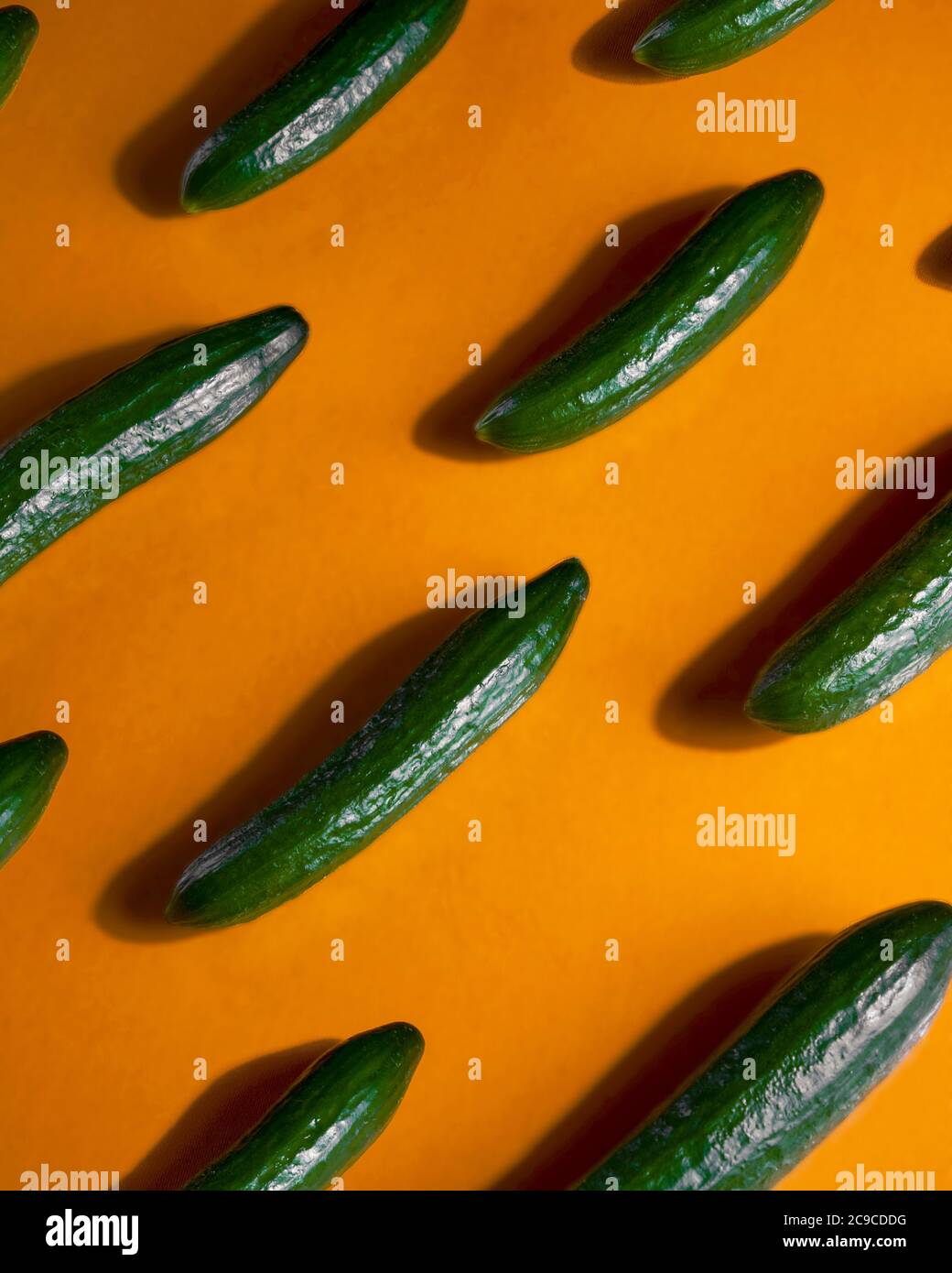 Pattern of fresh cucumbers on orange surface Stock Photo