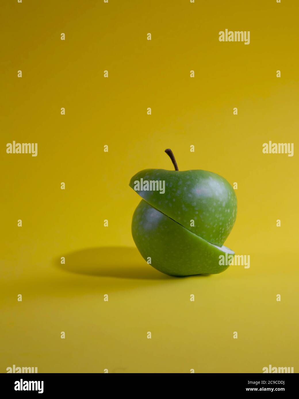 Cut green apple isolated on yellow background Stock Photo