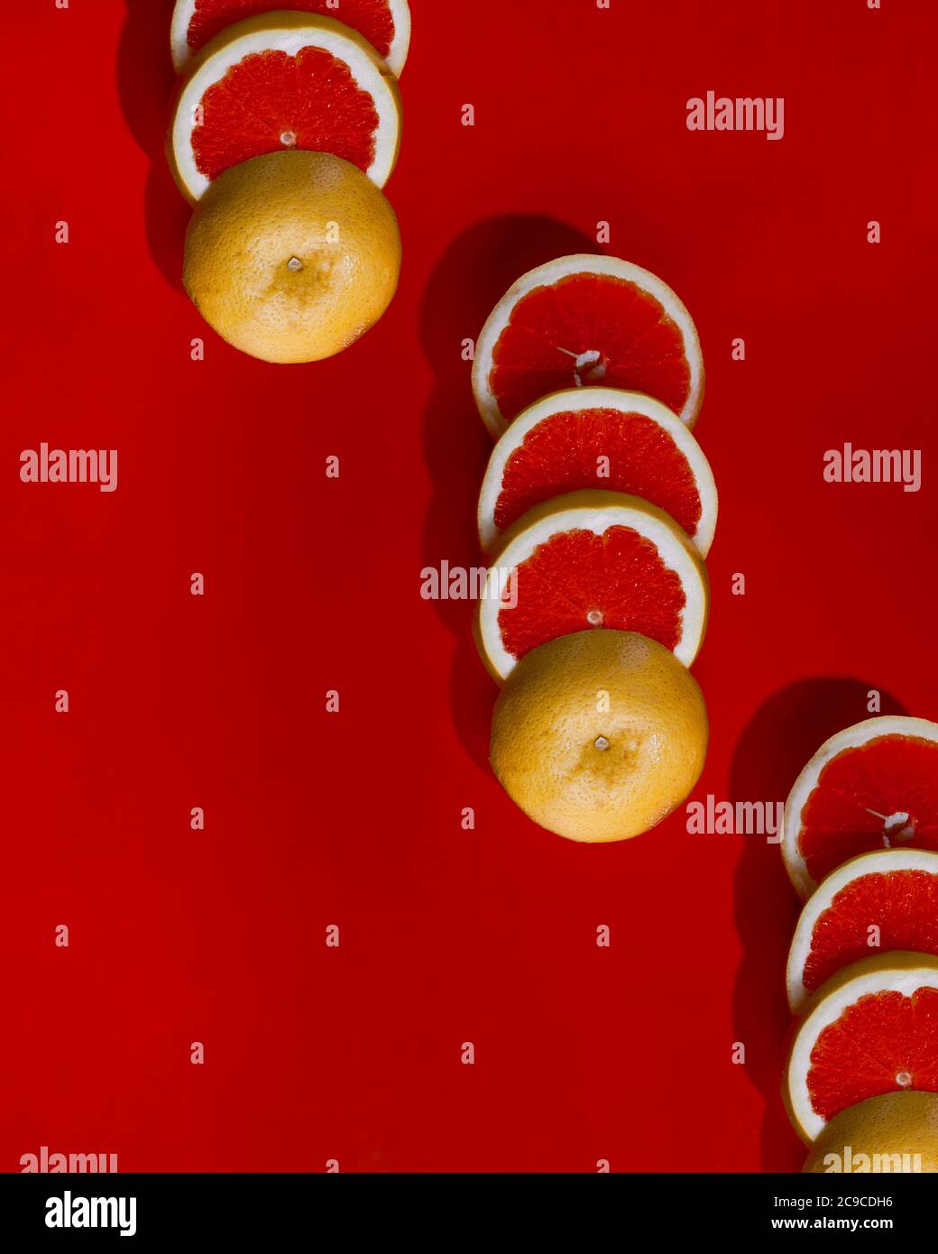 Pattern of sliced grapefruit on red surface Stock Photo