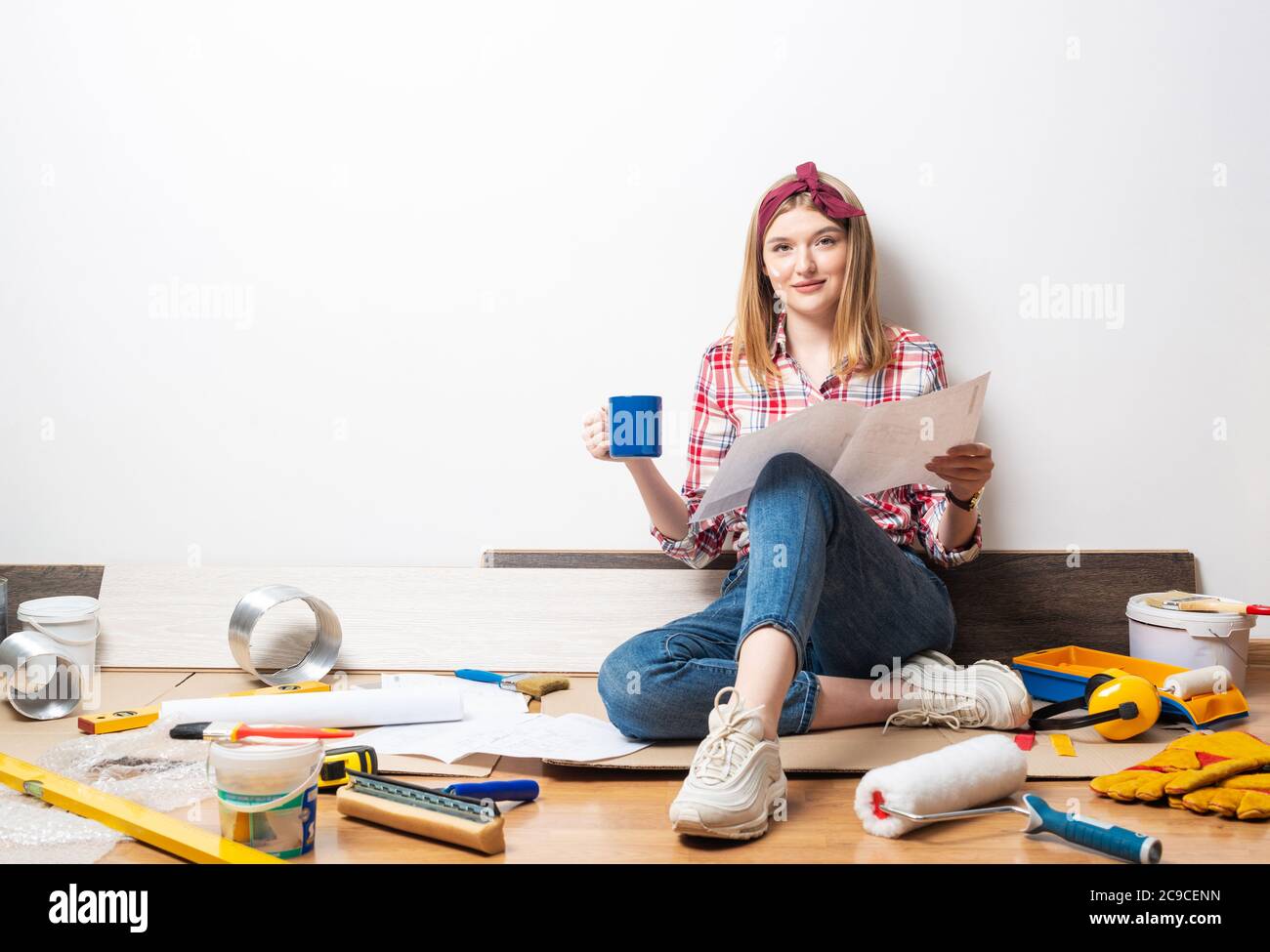 Smiling girl sitting on floor with blueprint Stock Photo - Alamy