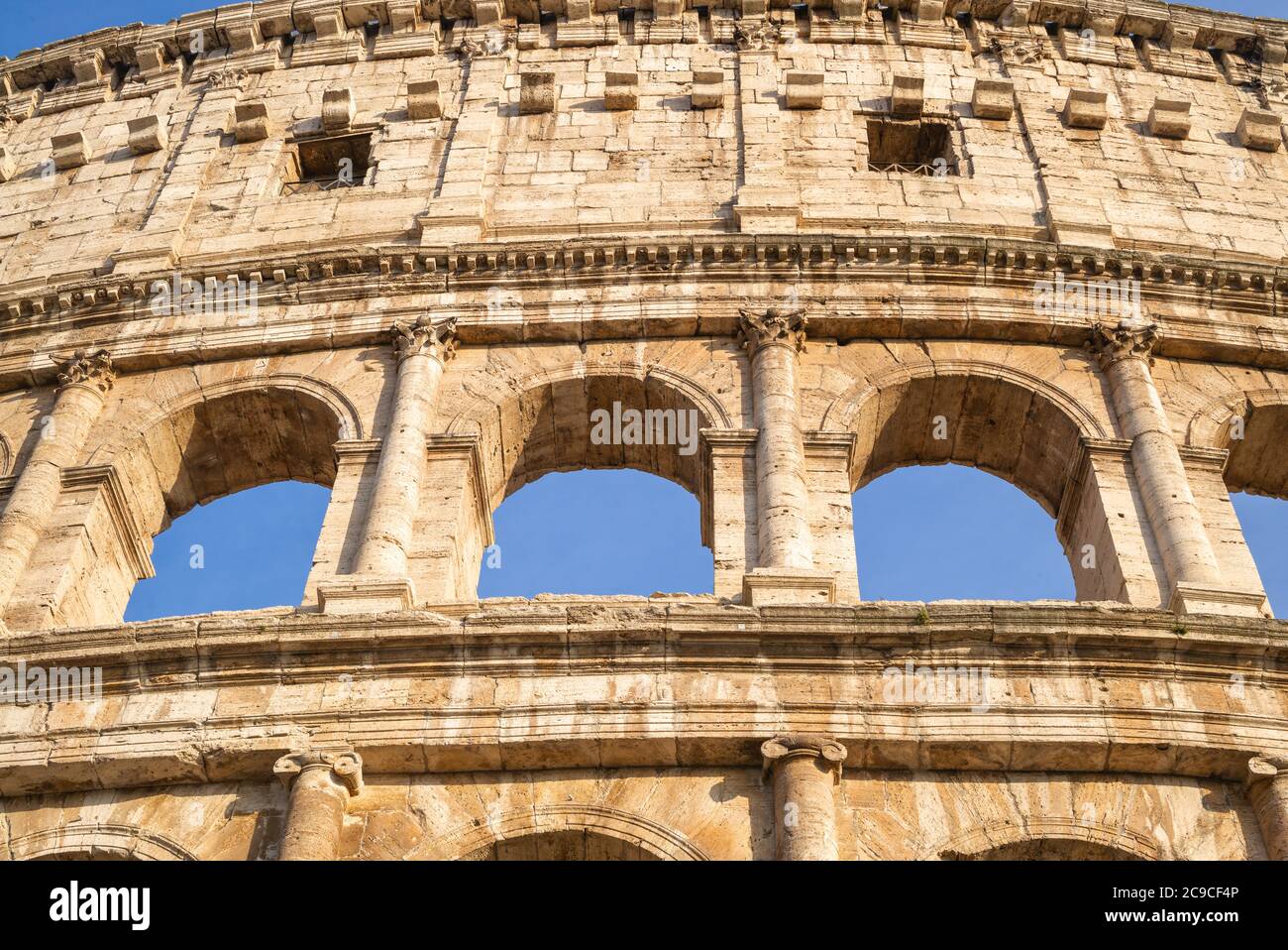 Graphic close-up of a section of the Coliseum / Colosseum set against blue sky in Rome, Italy Stock Photo