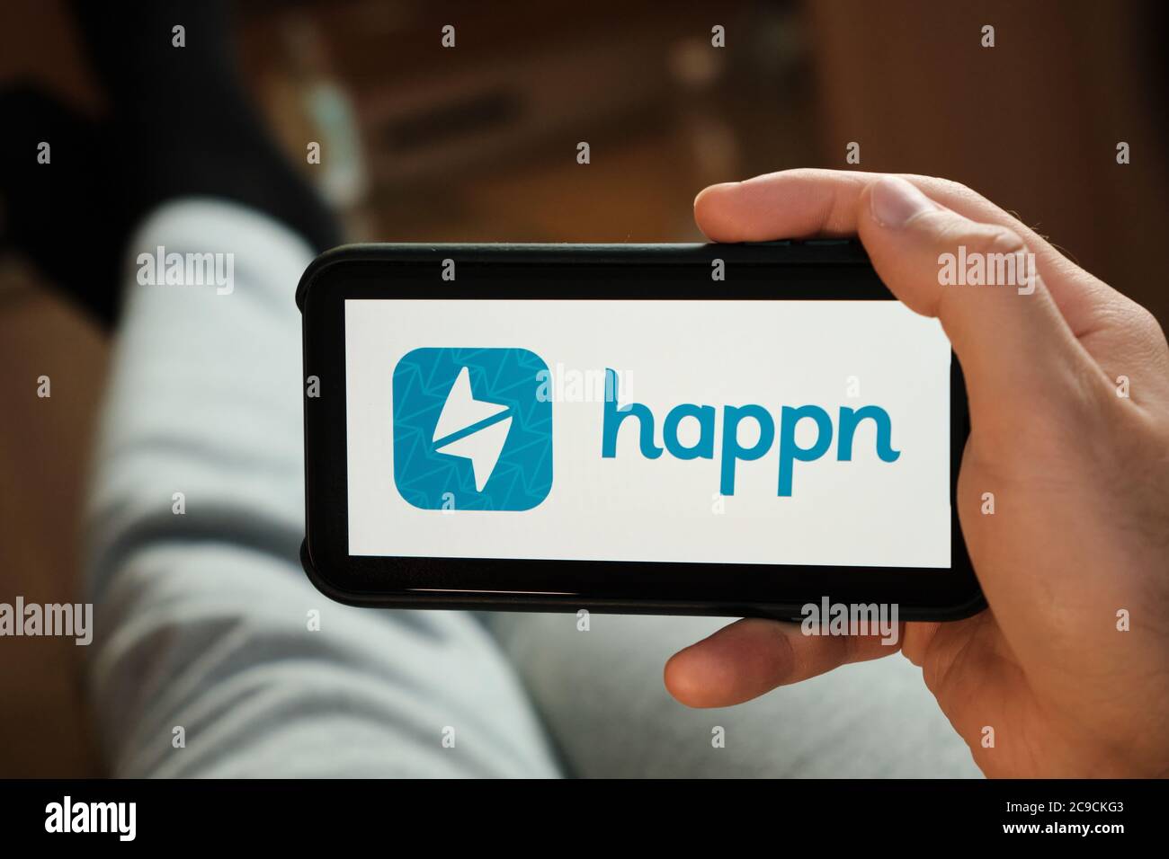 Happn application on the smartphone in mans hand. Man laying and using application for dating and meeting. Social network concept, July 2020, Prague Stock Photo