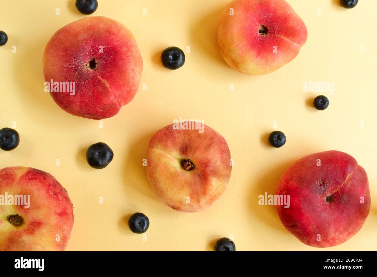 Peach on a yellow background. Juicy ripe peach and blueberry. Creative minimalistic food concept. Stock Photo