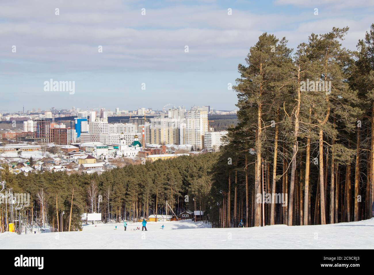 The training slope of the sports complex on Uktus Mountain framed by a pine forest. In the background a panorama of the city of Yekaterinburg, Russia Stock Photo