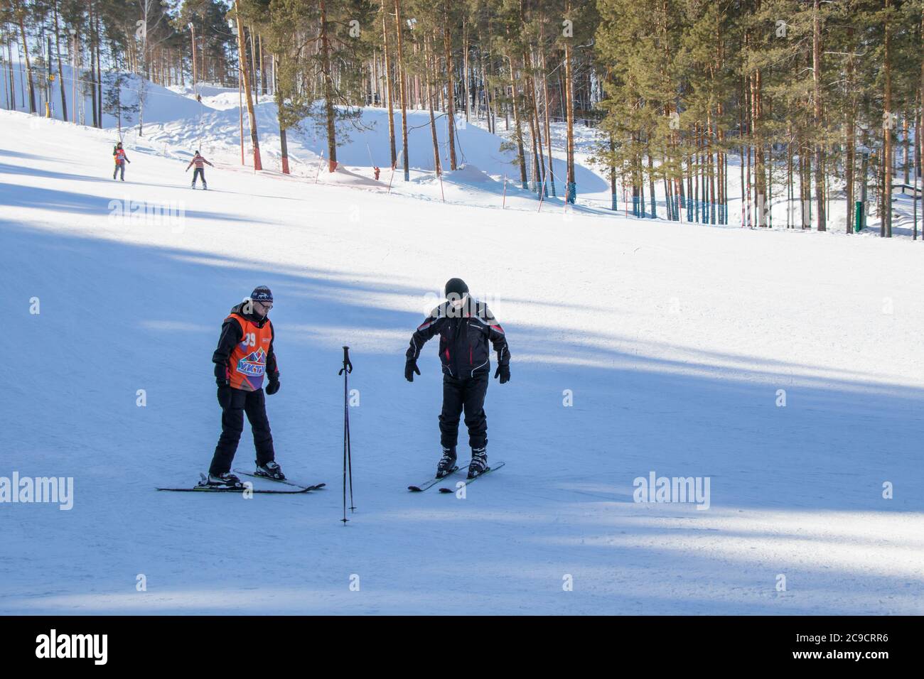 Yekaterinburg, Russia - February 26, 2019. Training slope of the sports complex on Uktus Mountain. A elder trainer teaches a man skiing. Stock Photo