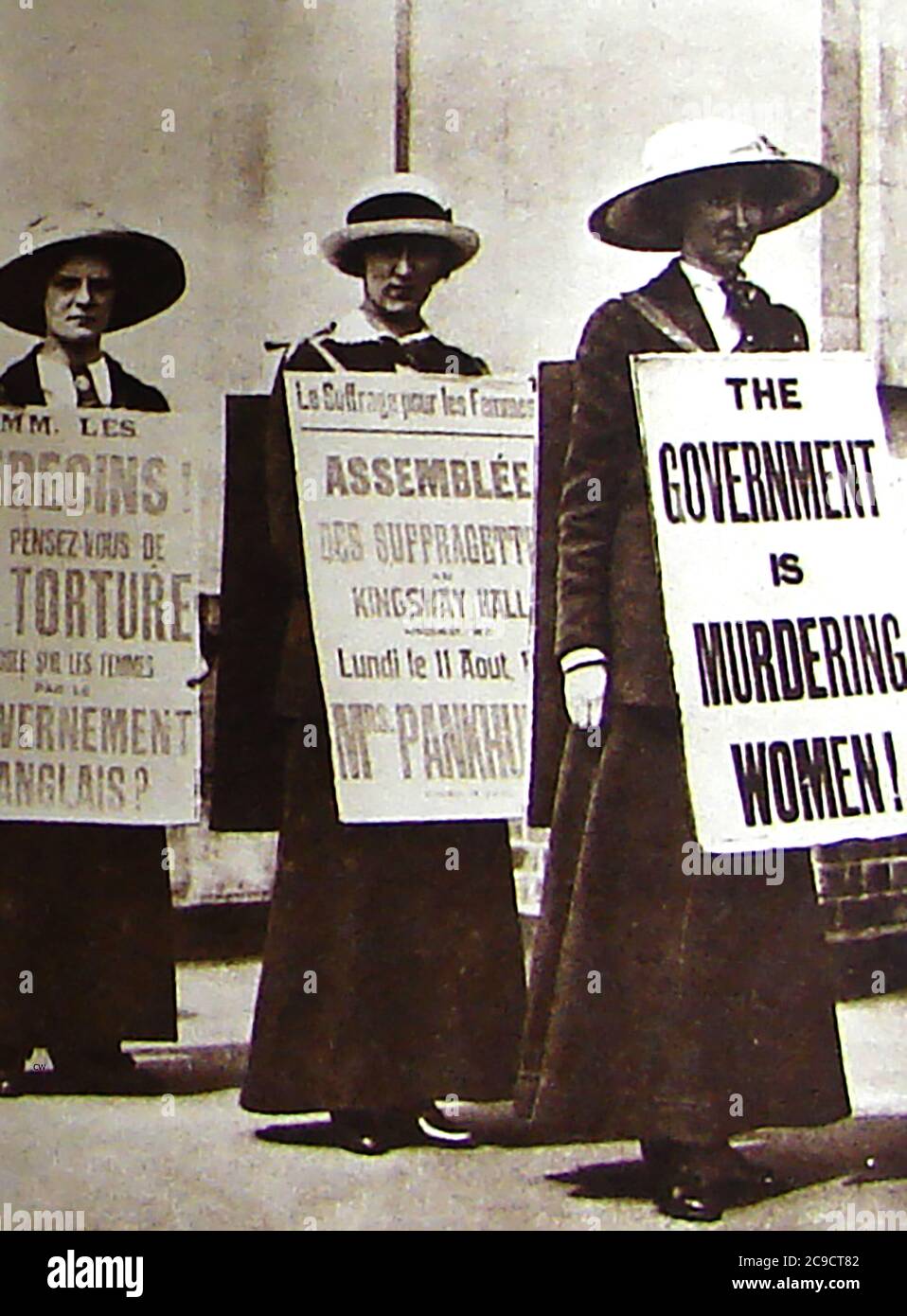 Three British militant suffragettes parading with  slogans on 'sandwich boards' in French and English such as 'The government is Murdering Women'. Stock Photo