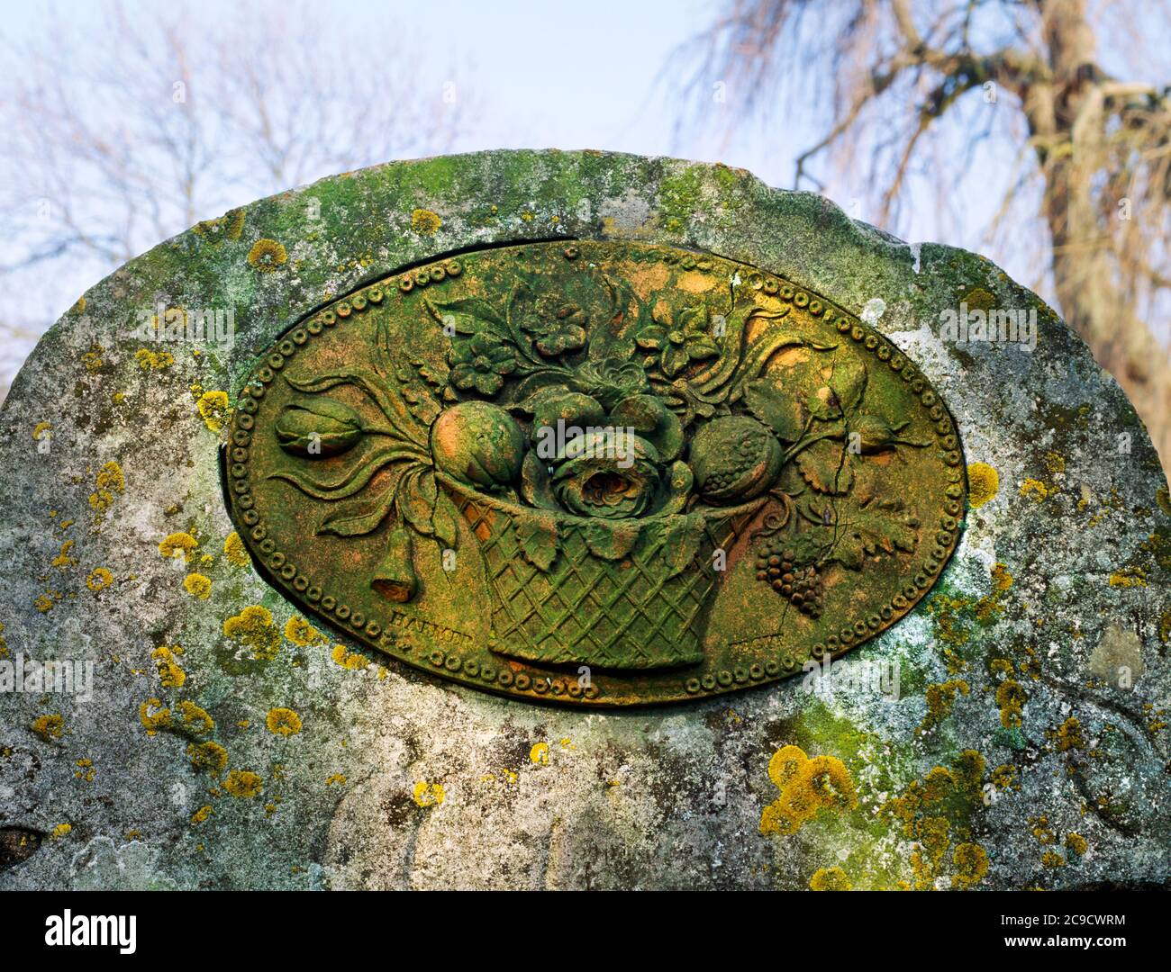 Brookland church, Kent. A terracotta relief plaque by Jonathan Harmer depicting a basket of flowers and fruit, set into the top of a headstone. Stock Photo