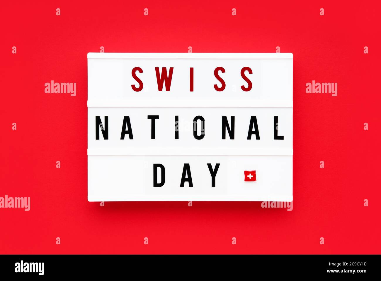 SWISS NATIONAL DAY written in a lightbox on a red background. Independence day date. Top view. Stock Photo