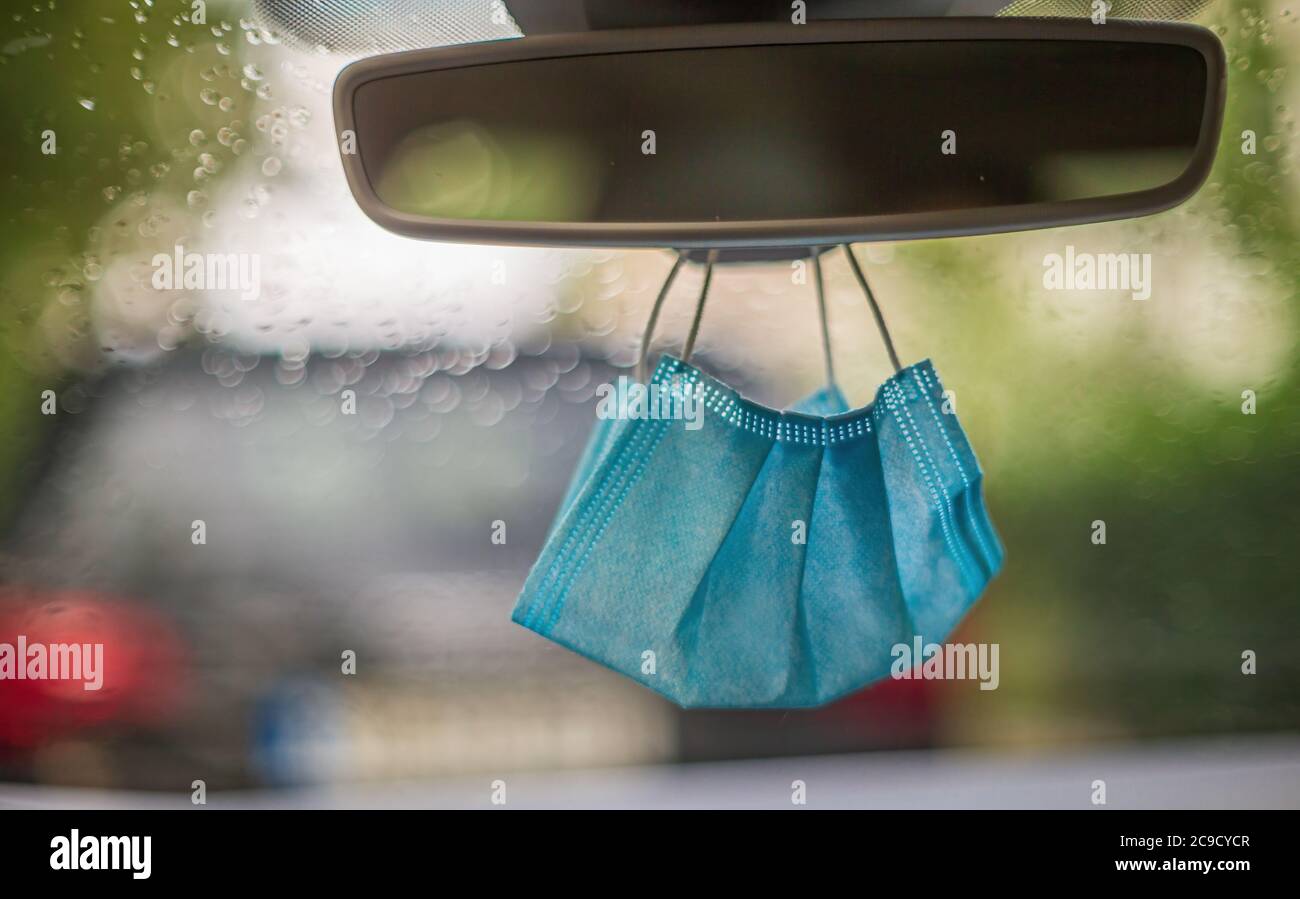 Protective face mask hanging at the rear mirror in a car Stock Photo