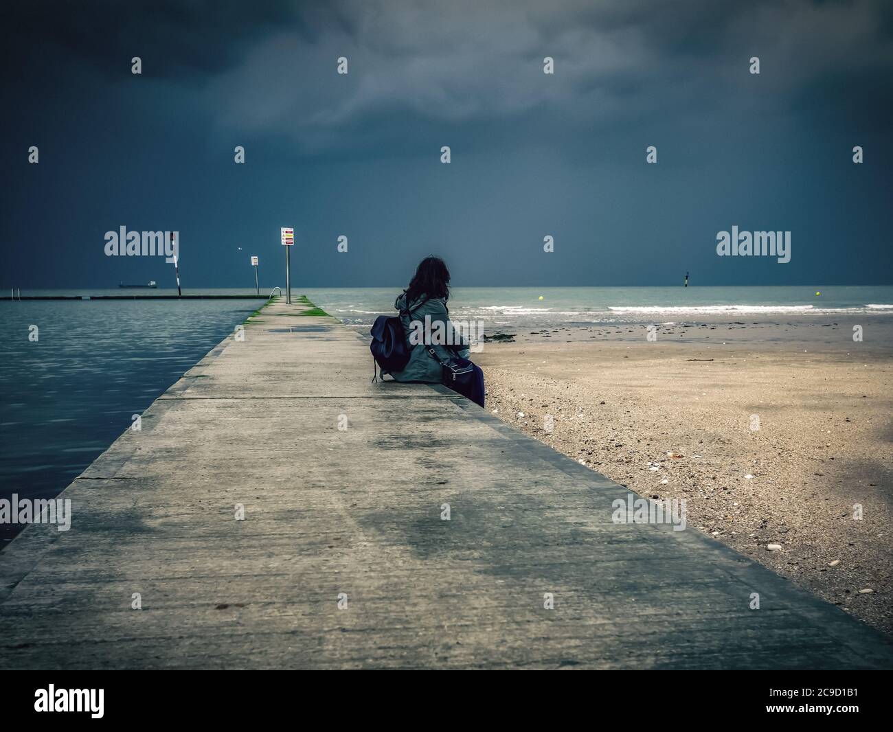 Woman sitting on a wall watching the sea Stock Photo - Alamy