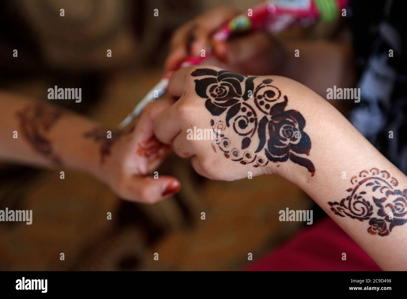 Sanaa, Yemen. 30th July, 2020. A girl gives her sister henna designs