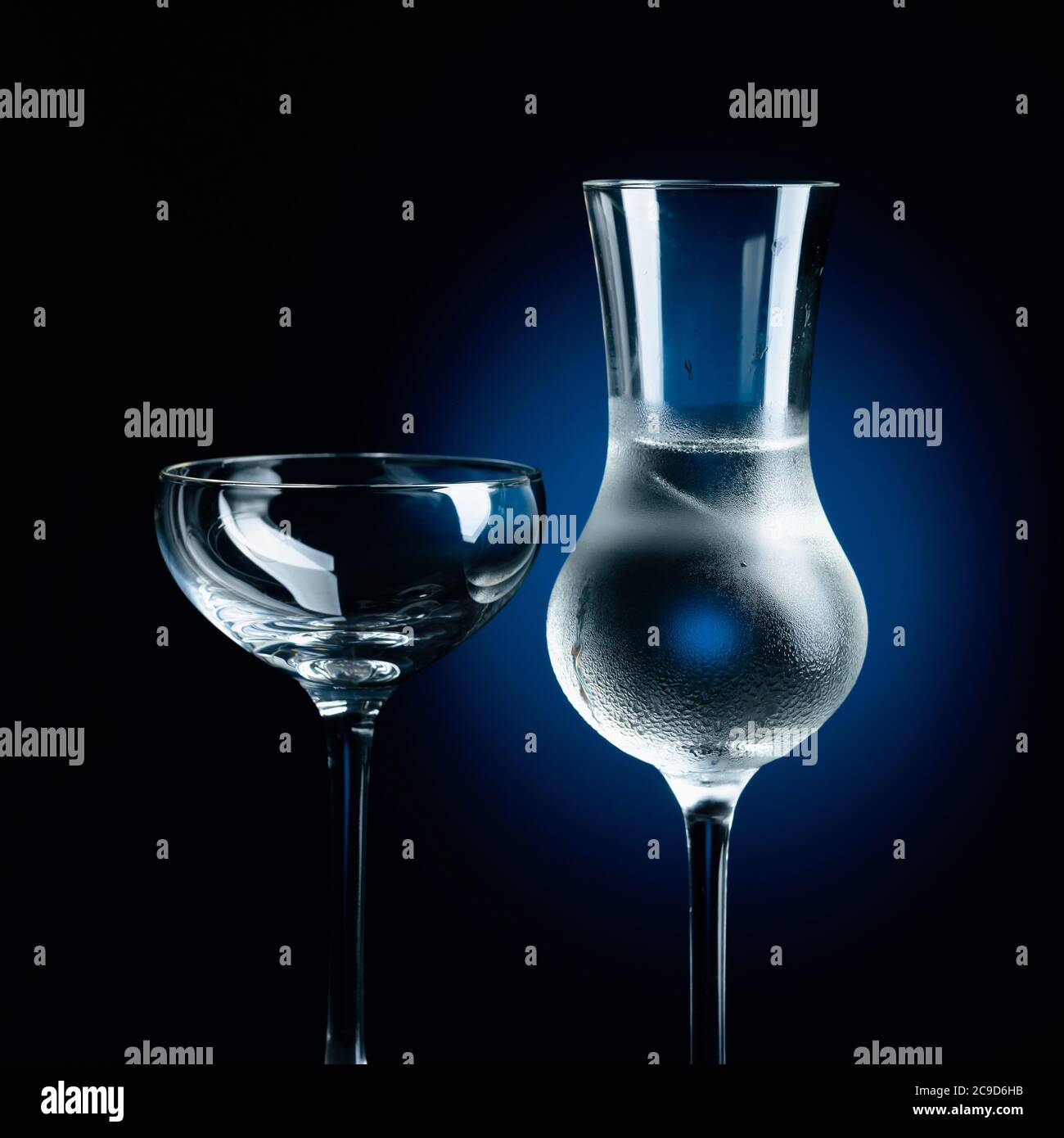 Strong alcoholic drink in frozen glass with ice. Frozen glasses on a dark blue background. Stock Photo