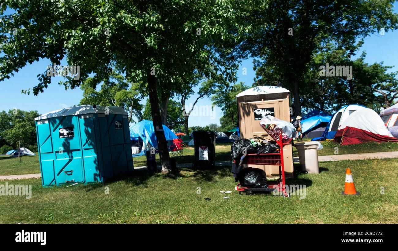 Homeless encampment, outdoor toilets, garbage bin and full plastic bags at Powderhorn Park. Minneapolis Minnesota MN USA Stock Photo