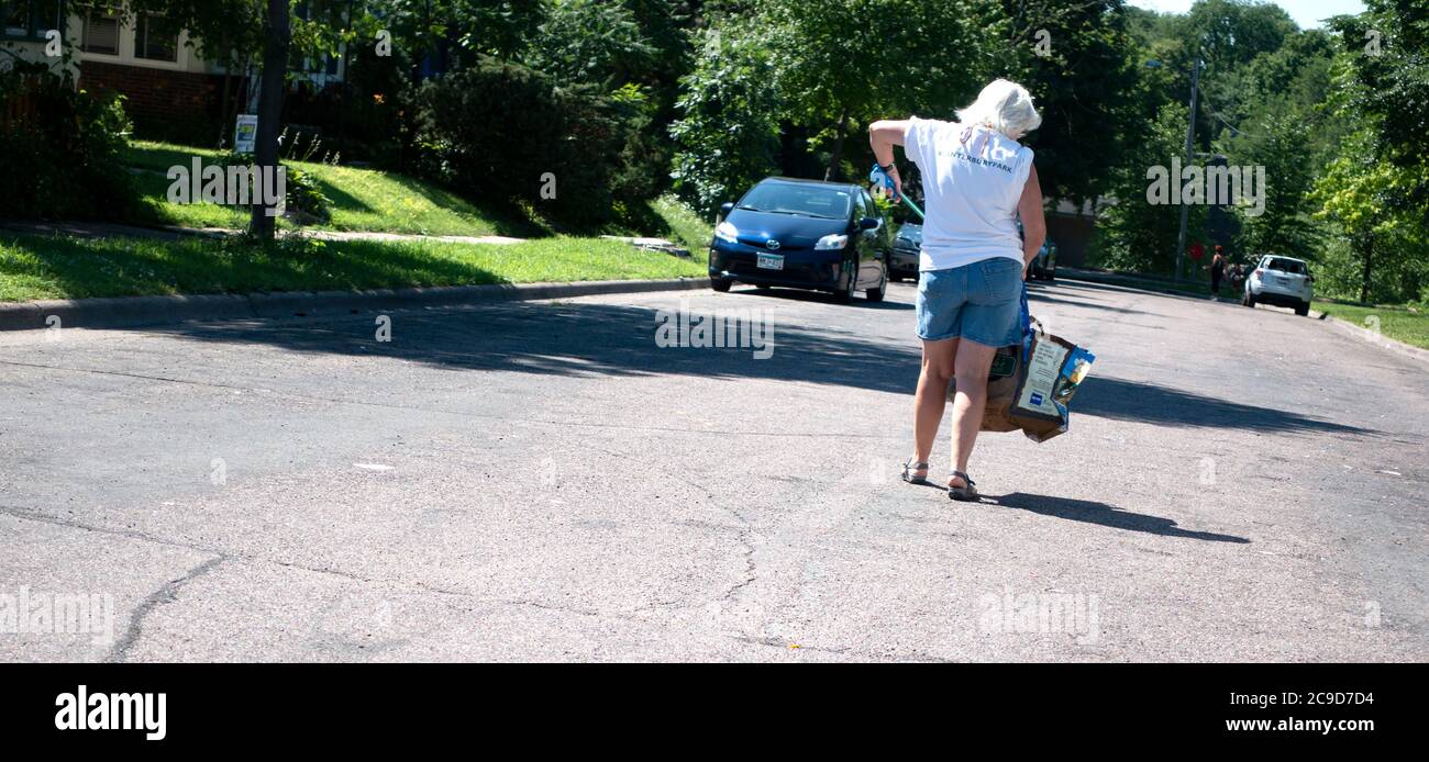Volunteer picking up trash in the street by Powderhorn Park at the homeless encampment. Minneapolis Minnesota MN USA Stock Photo