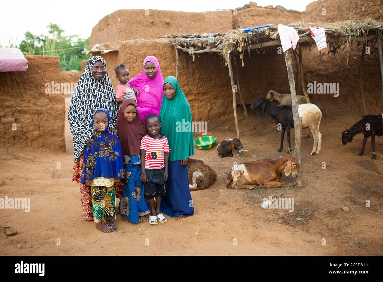 A woman farmer and her children stand with their herd of sheep and ...