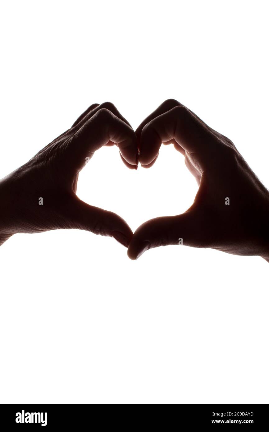 Female and male hands as a symbol of the heart - vertical silhouette Stock Photo
