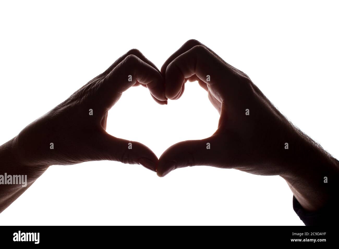 Female and male hands as a symbol of the heart - horizontal silhouette Stock Photo
