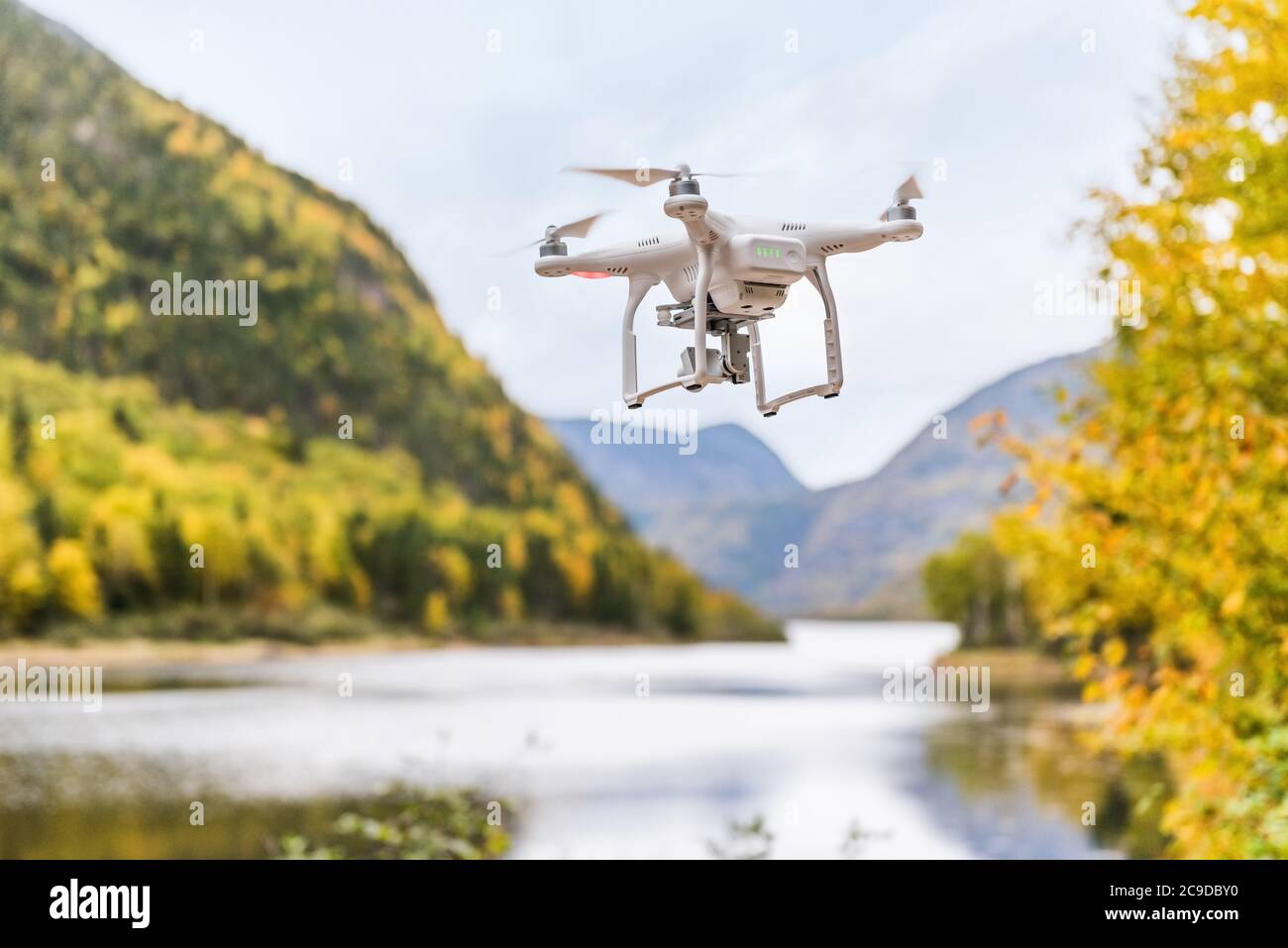 Drone uav flying in the air taking video of autumn forest foliage nature landscape in outdoors during fall season. Quad copter with digital camera Stock Photo