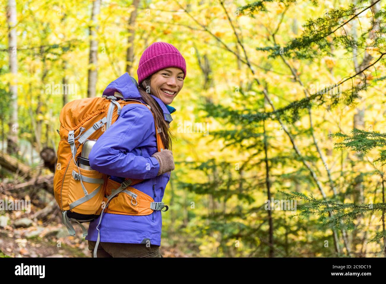 Happy backpacker girl hiking in autumn forest. Young asian hiker