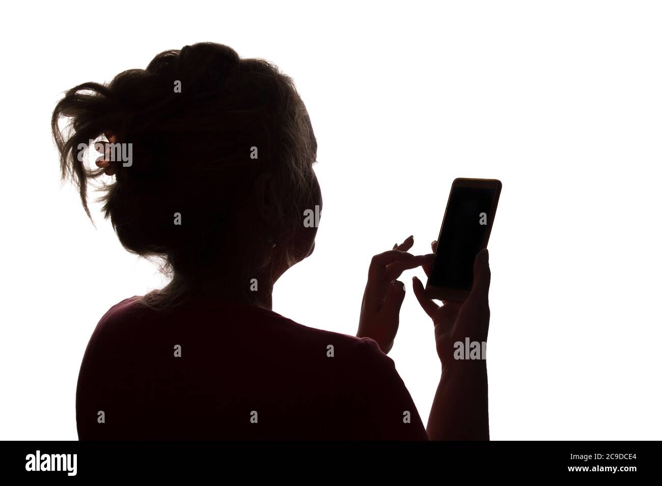Silhouette of a girl from the back with a mobile smart phone - isolated, technology Stock Photo