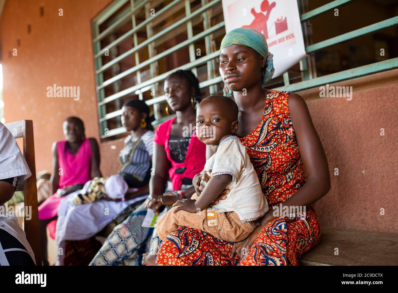 A mother and her young child wait to be seen at a health center in Kouroussa, Guinea, West Africa. Stock Photo