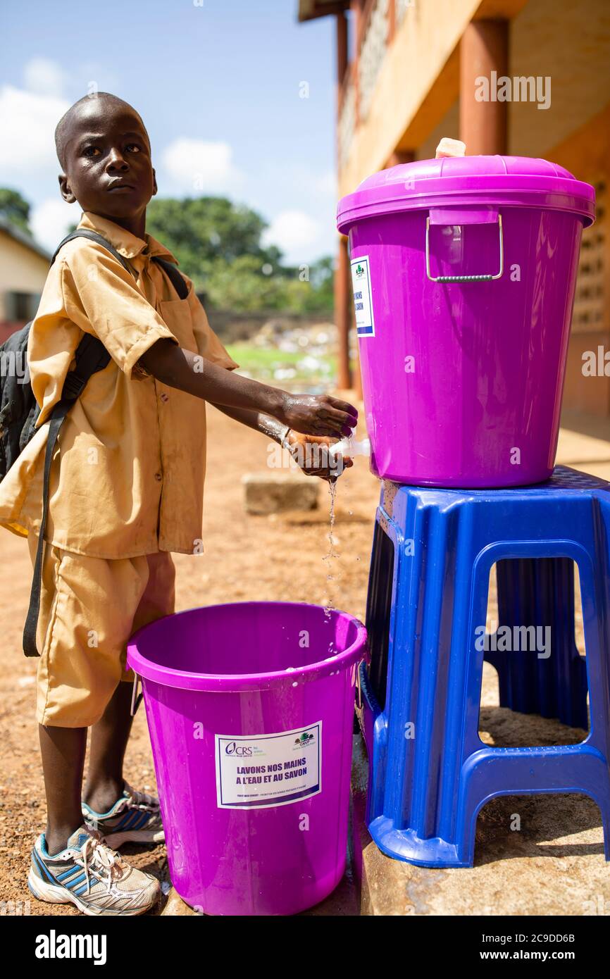 A boy child washes his hands at a hand washing station at his school in Conakry, Guinea, West Africa. Stock Photo