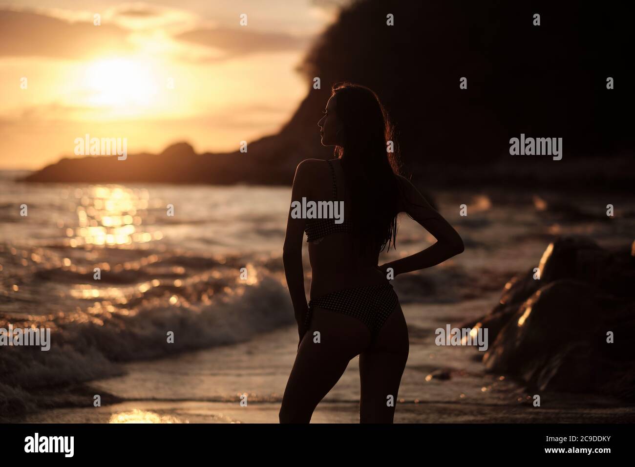 Sunset silhouette of young woman at a beach Stock Photo
