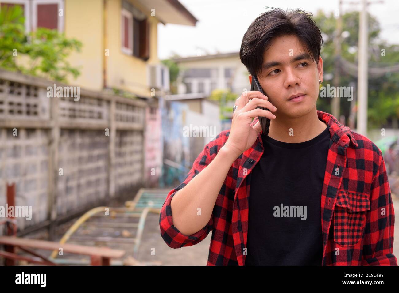 Young handsome Asian hipster man talking on the phone in the streets outdoors Stock Photo