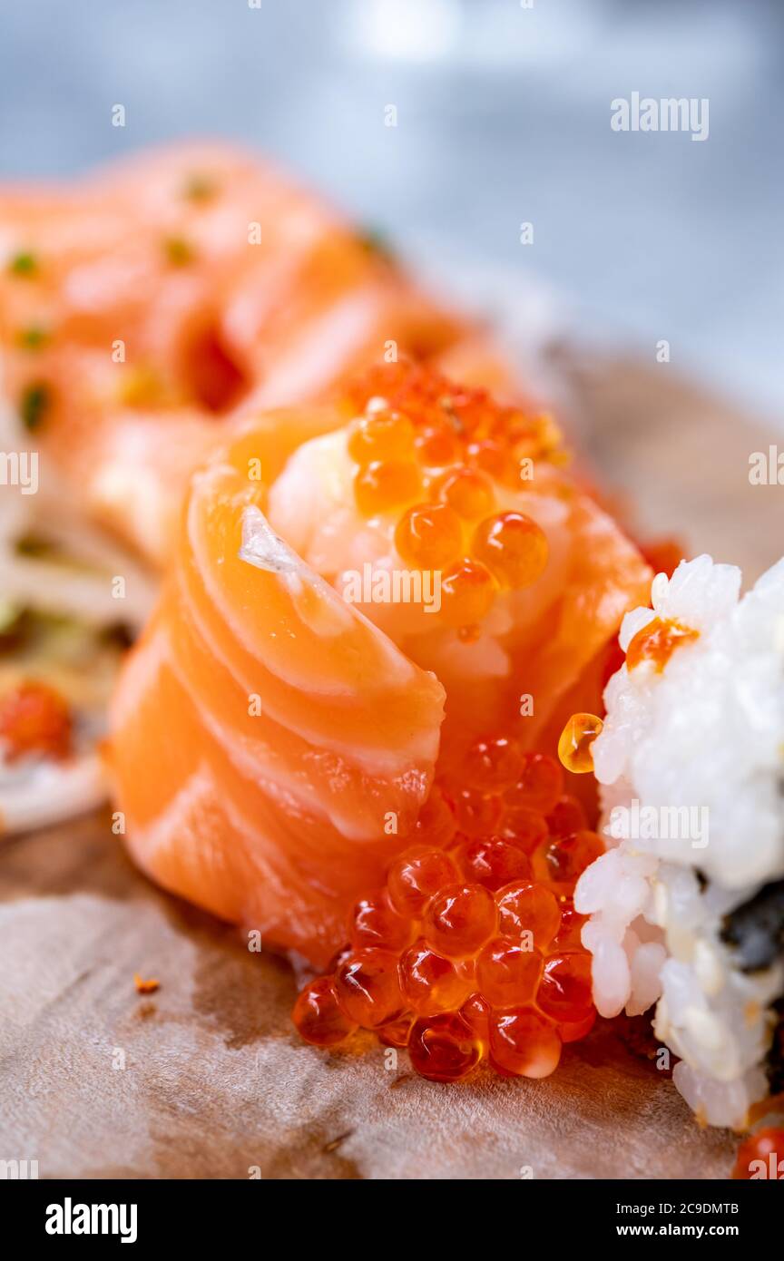 Japanese food, fresh sushi or sashimi made from rice with salmon, avocado, cucumber, red fish caviar, tempura shrimps close up Stock Photo