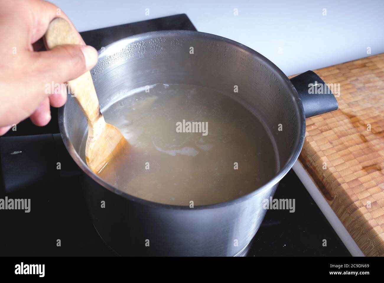 Mixing together ingredients of hot-water crust pastry dough, using wooden  spoon Stock Photo - Alamy