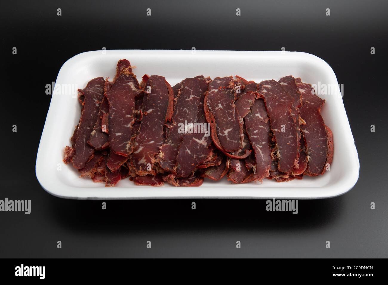 Turkish traditional pastirma (pastrami) in a white styrofoam container isolated on black background with copy space for text Stock Photo
