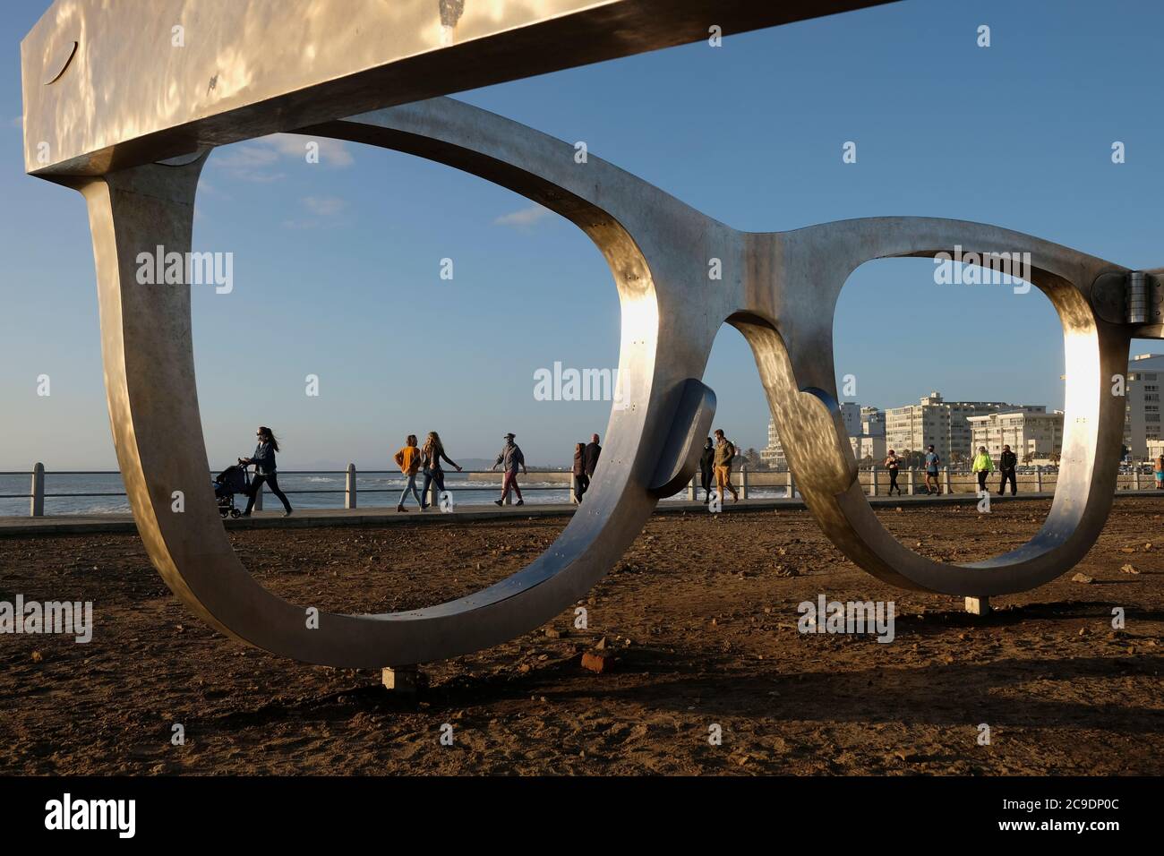 Everyday life on the promenade with Michael Elion's Madiba (Nelson Mandela) inspired public sculpture 'Perceiving Freedom' in Sea Point, Cape Town. Stock Photo