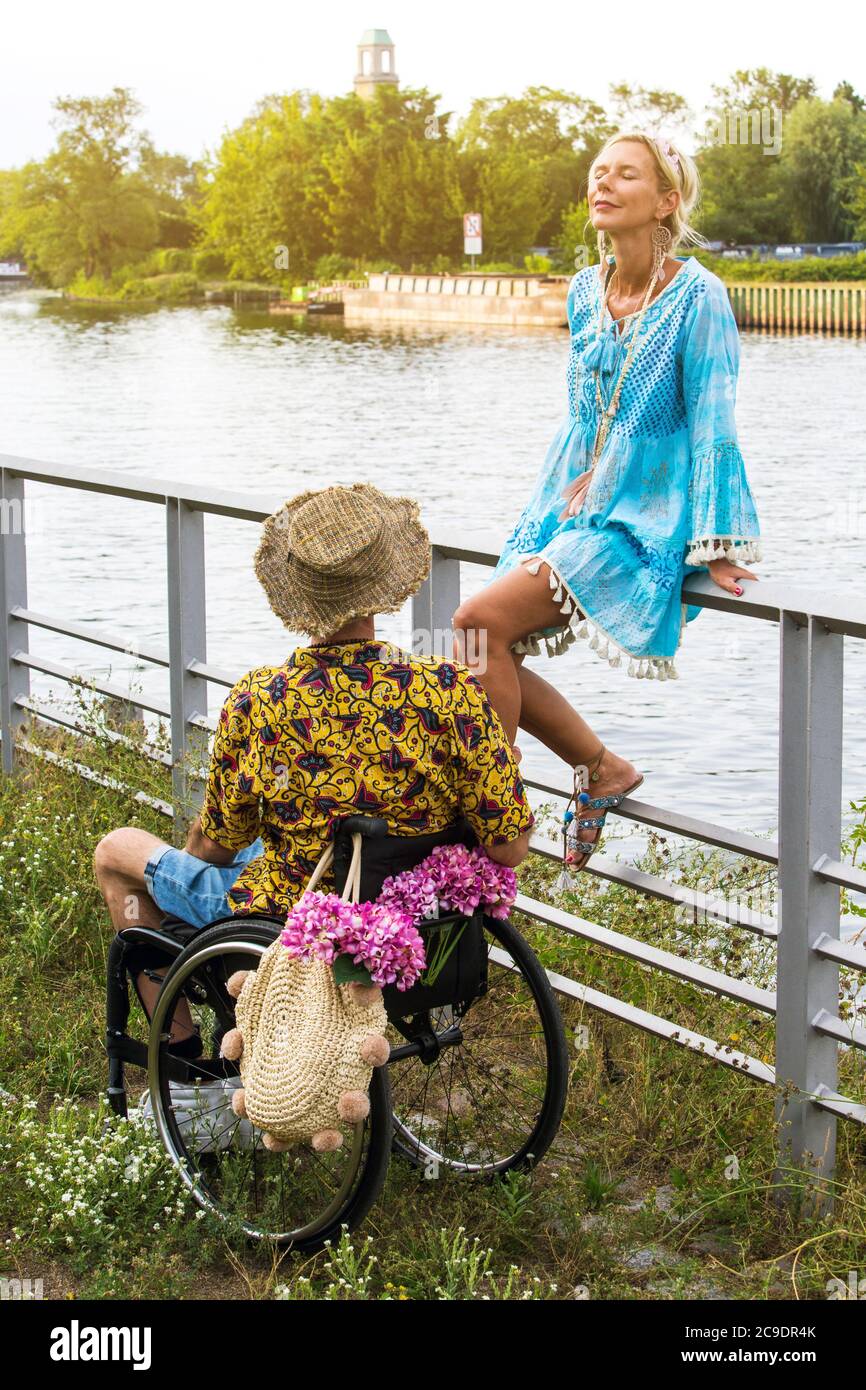 blond woman sitting by river enjoying the sun next to a young man in ...