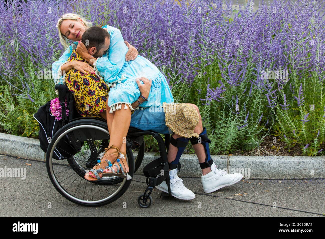 young man in wheelchair with woman sitting on his lap and hugging him ...