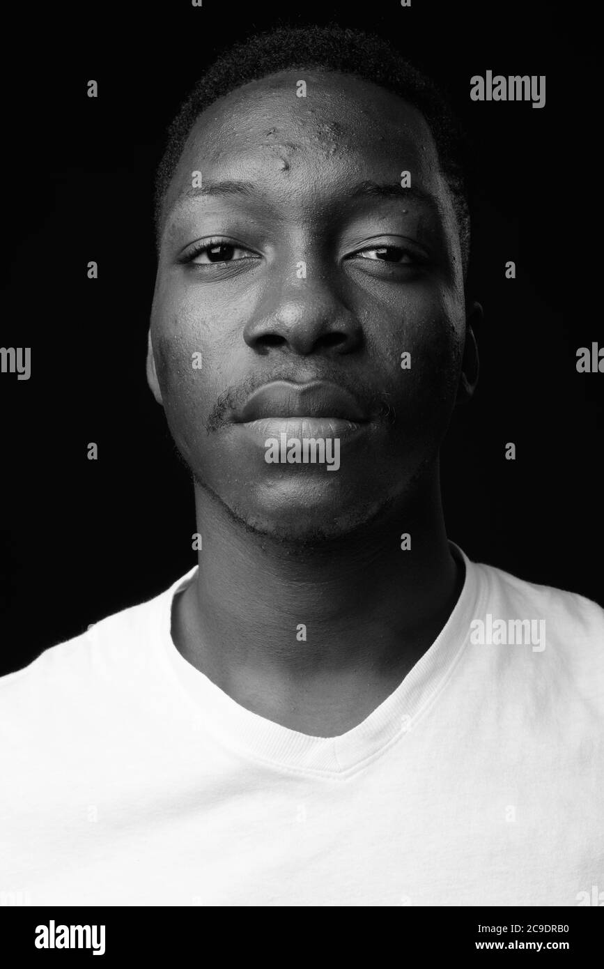 Young handsome African man against black background in black and white ...