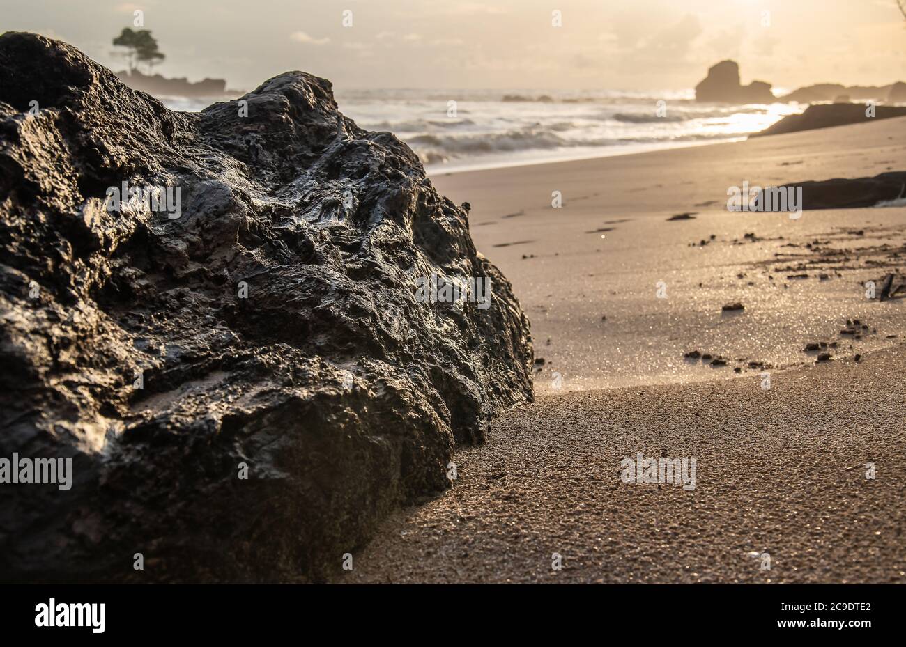 Black big rock lying on a beach in Africa's gold coast Ghana West Africa at a sunset Stock Photo
