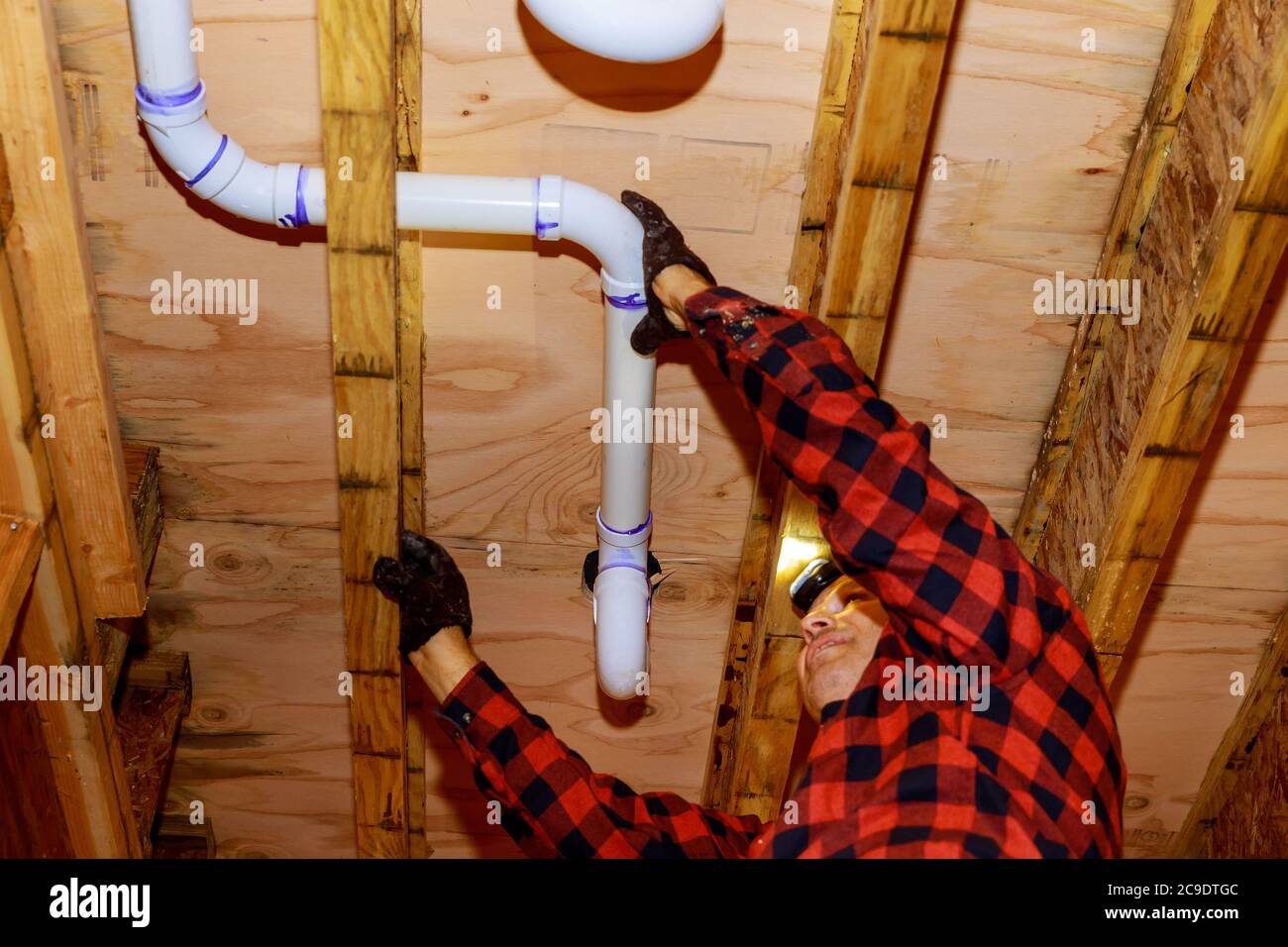 Workers are sewer toilet pipes with PVC joints allows the split the make PVC pipe coming out the other side the buildingceiling beam house. Stock Photo