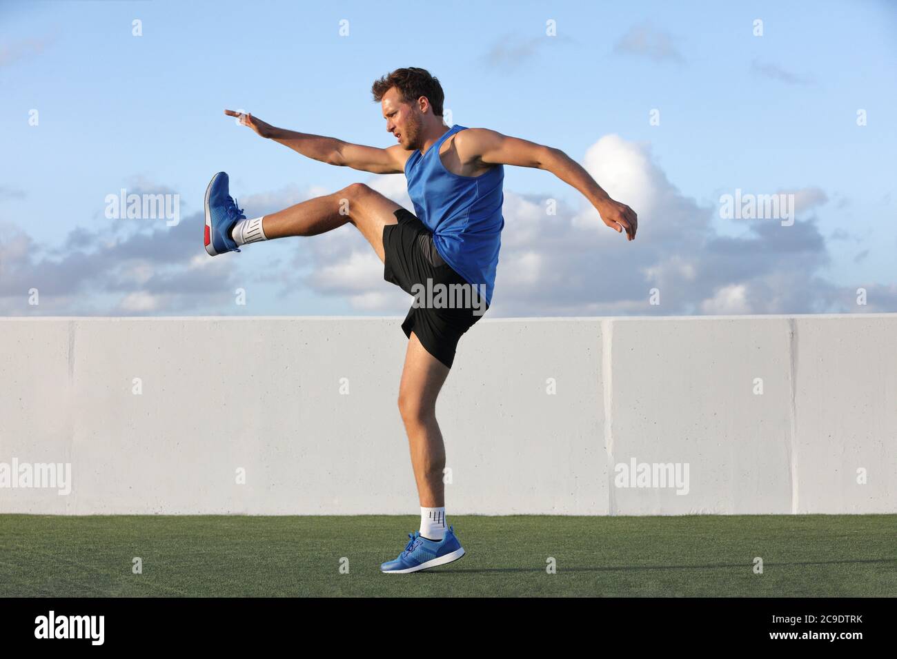 Runner man getting ready to run doing warm-up dynamic leg stretch exercises routine, Male athlete stretching lower body hamstring muscles before going Stock Photo