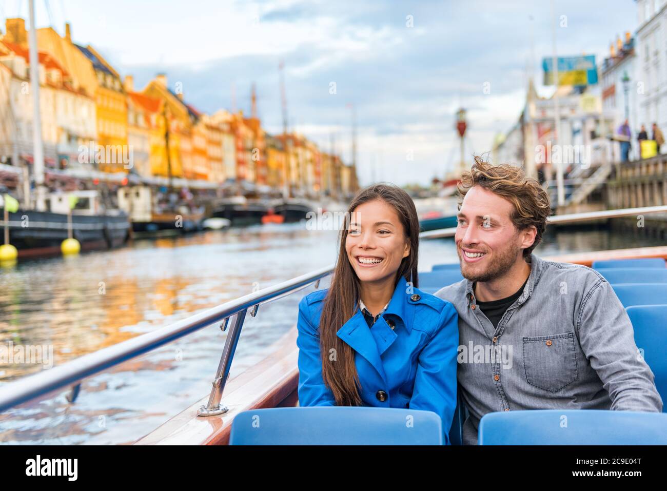 Copenhagen tourists people on Denmark travel holiday cruise boat tour in old port. Young multiracial couple travelers relaxing enjoying view of Nyhavn Stock Photo