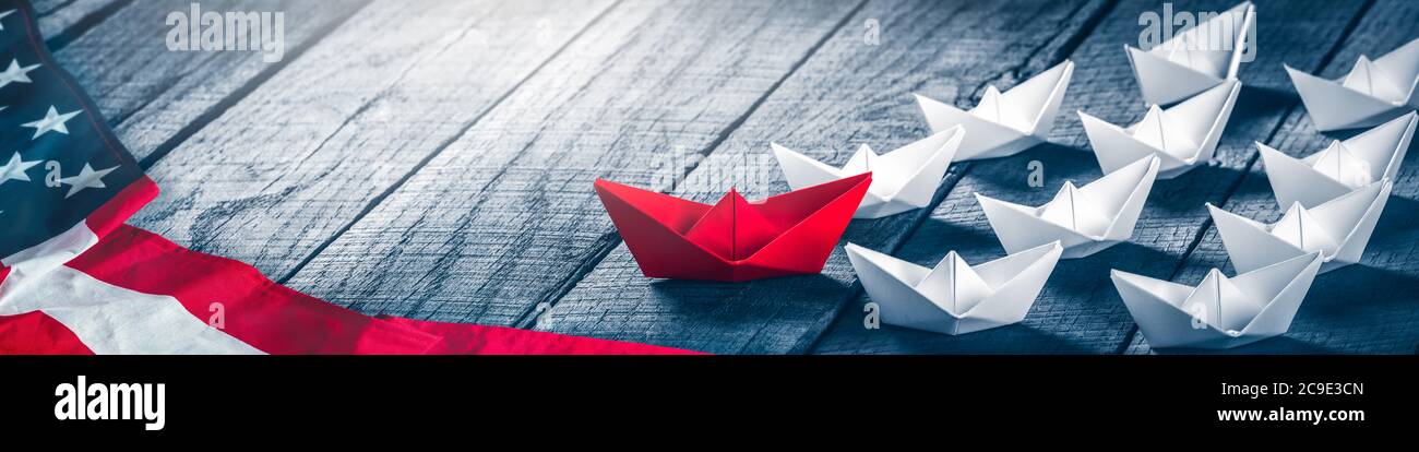 Red Paper Boat Leading A Fleet Of Small White Boats With American Flag On Wooden Table - Republican Leadership / Election Concept Stock Photo