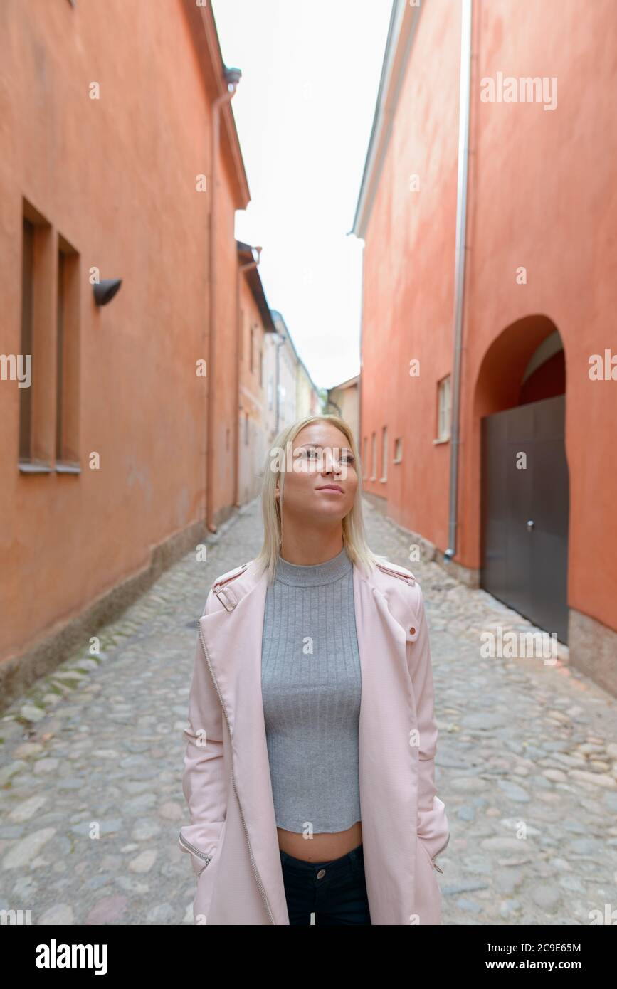 Young beautiful blonde woman thinking along the alley in the city Stock Photo
