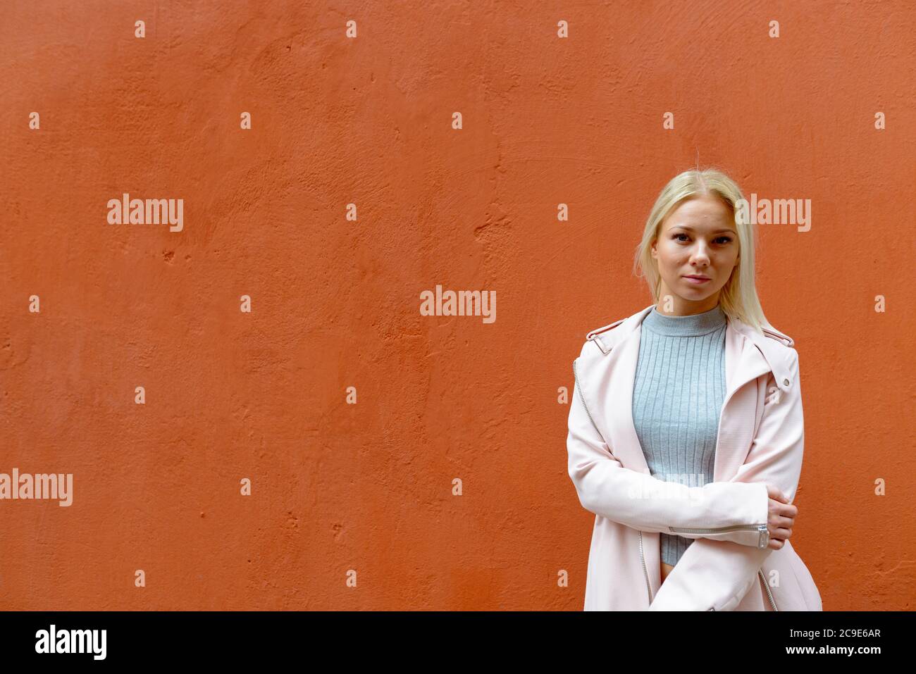 Young beautiful blonde woman against orange wall outdoors Stock Photo