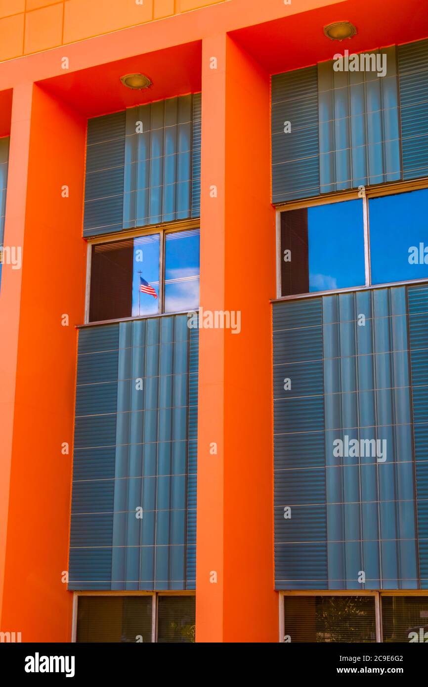 A bright orange  wall of windows in Los Angeles reflects an American flag in the sky. The architecture accents the flag. Stock Photo