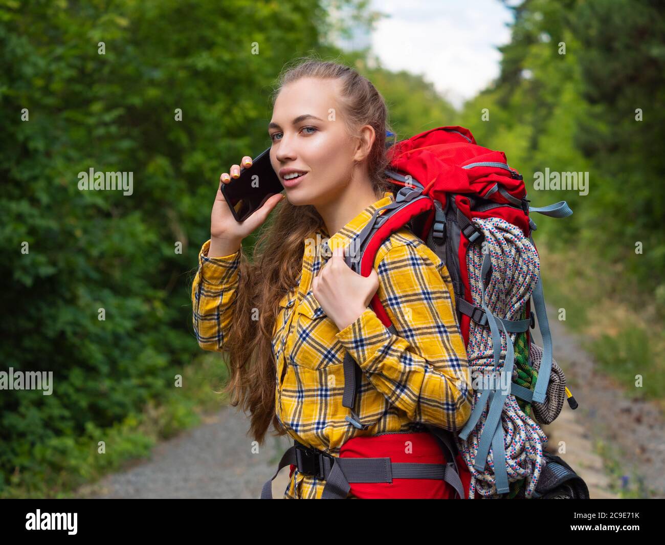 Young hiker woman using a smartphone in the forest. Ecotourism concept. Stock Photo