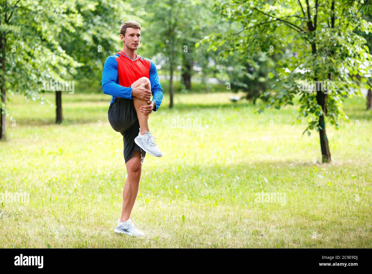 Sport and healthy lifestyle concept - jogger man stretcing muscles in public park. Stock Photo