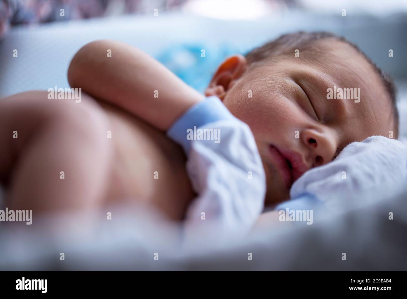 Shirtless newborn baby boy wearing white gloves sleeping Stock Photo