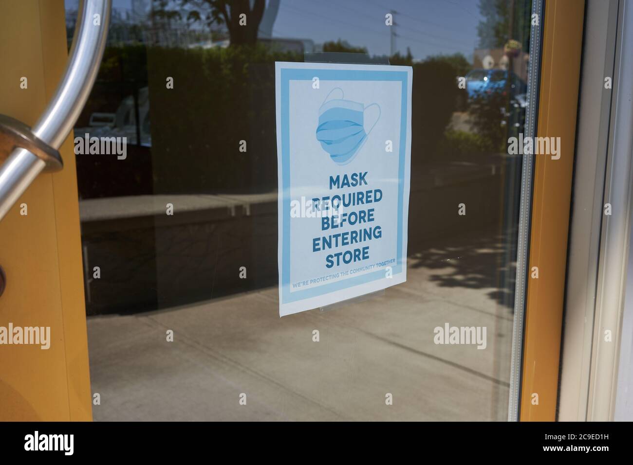 Mandatory mask policy signage at the entrance to a retail store during the coronavirus pandemic. Stock Photo