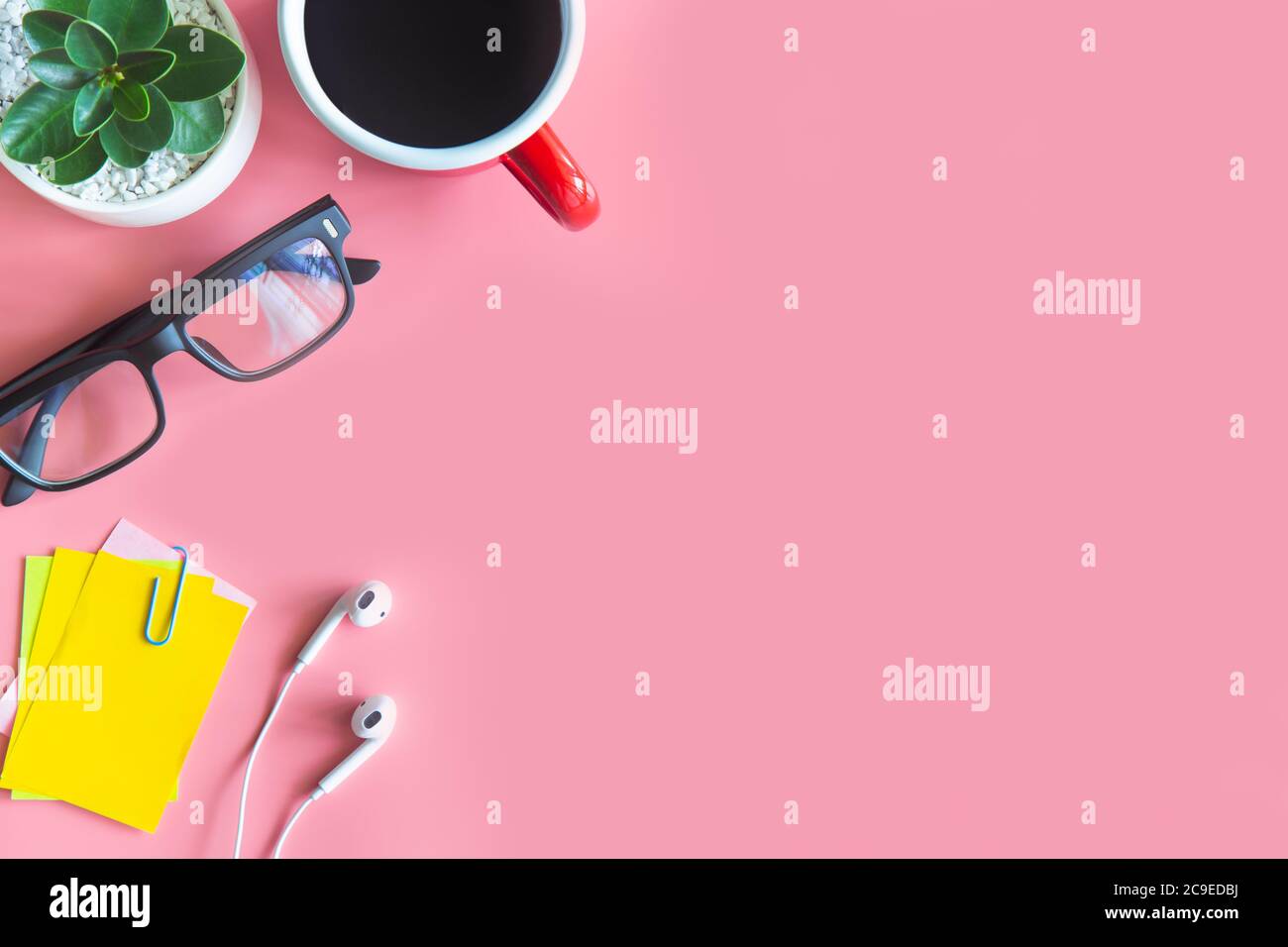 Pastel pink desk office with laptop, smartphone and other work supplies