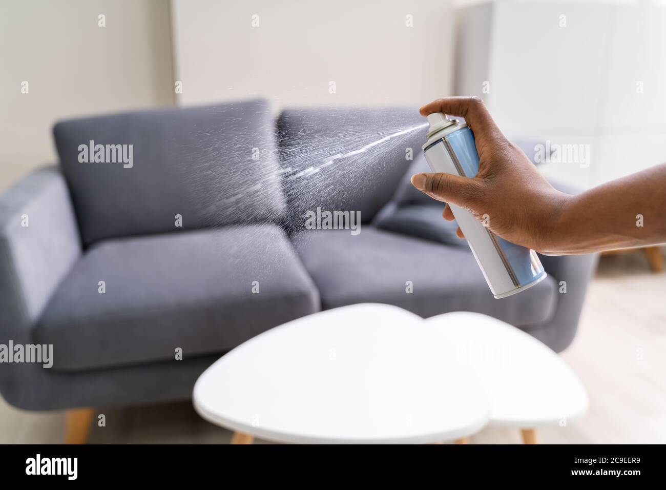 African Woman Using Living Room Air Spray Stock Photo